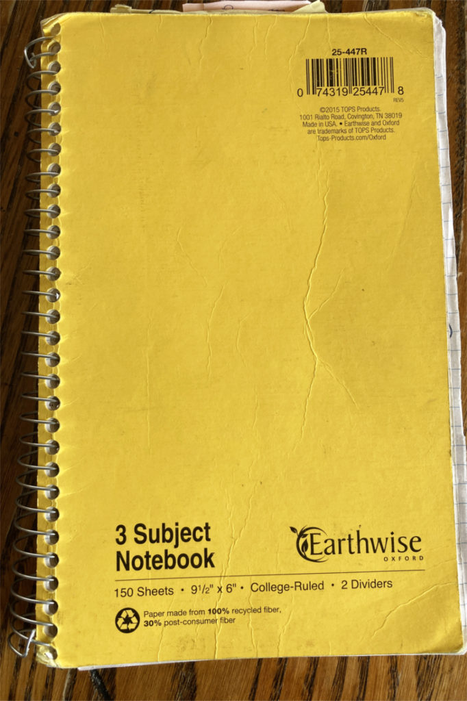 The author's songwriting notebook, a yellow Earthwise spiral-bound.